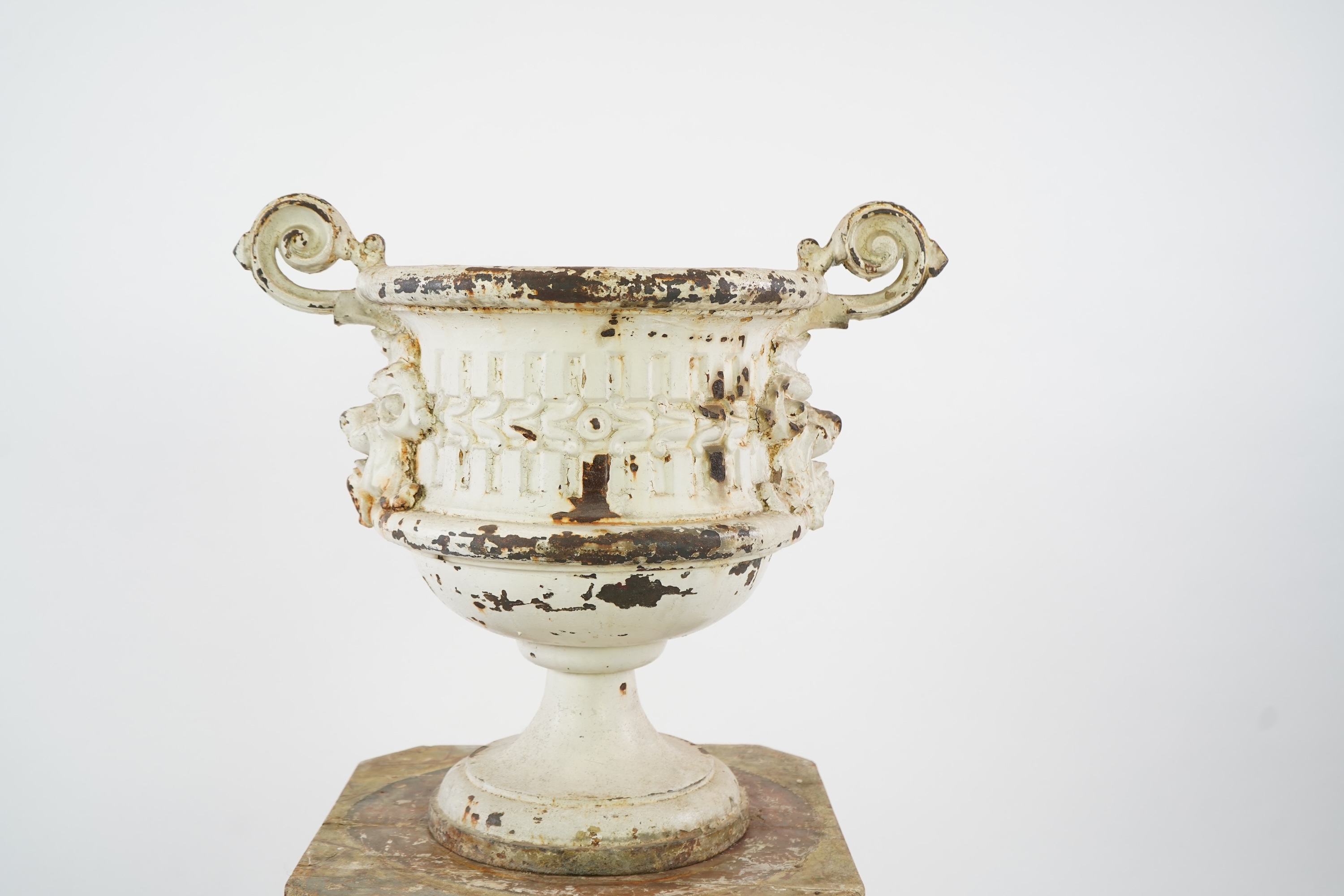 A Victorian white painted cast iron urn and a painted faux marble pedestal